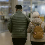 Kuvassa ikääntynyt pariskunta kävelee ostoskeskuksessa.