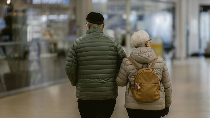 Kuvassa ikääntynyt pariskunta kävelee ostoskeskuksessa.