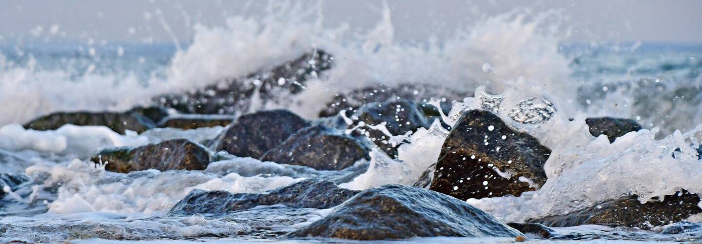 kiviä meressä, vaahotava vesi ympärillä.