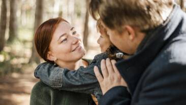 Vanhemmat halaavat lasta. Taustalla näkyy metsäistä maisemaa.